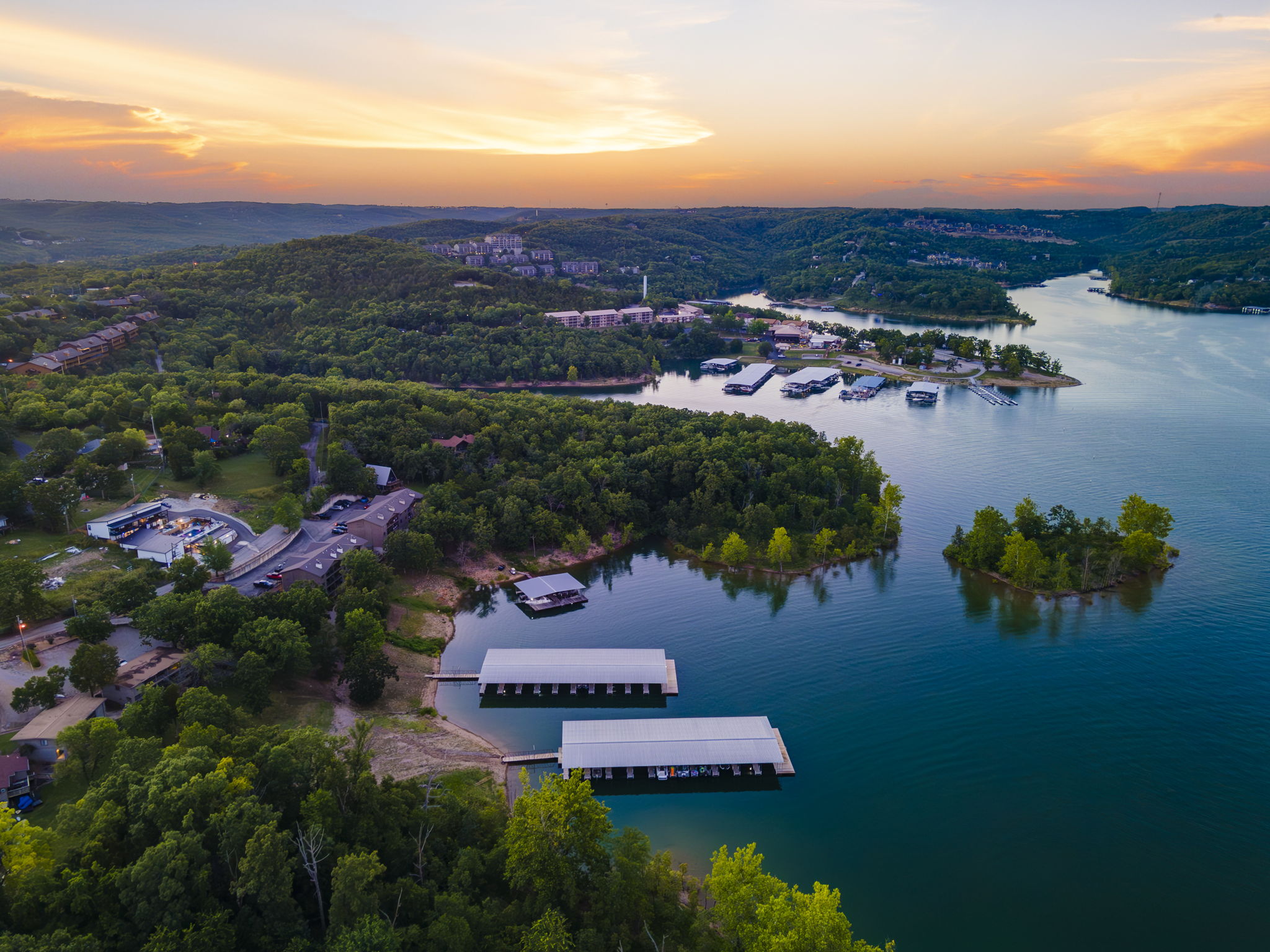 Aerial view of a Branson lake and wooded hills at sunset